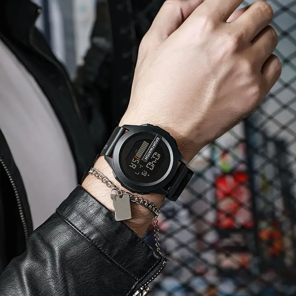 Hand wearing a black digital watch with a blurred background