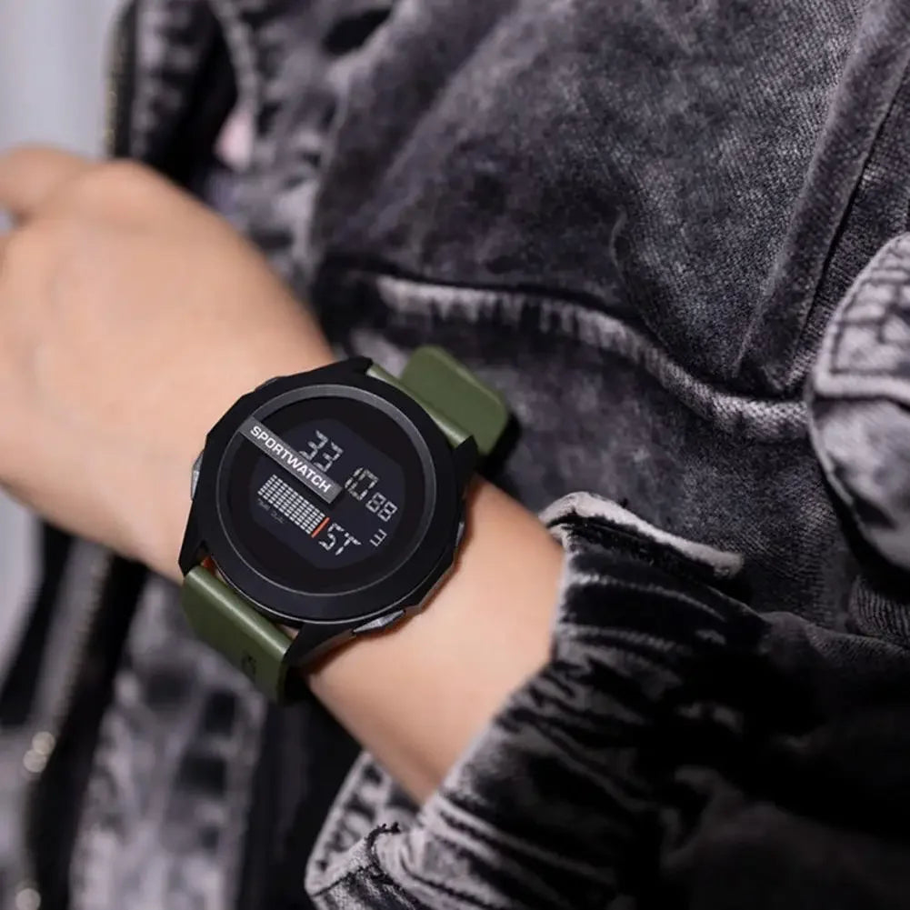 Person wearing a digital watch with a green strap on a blurred background